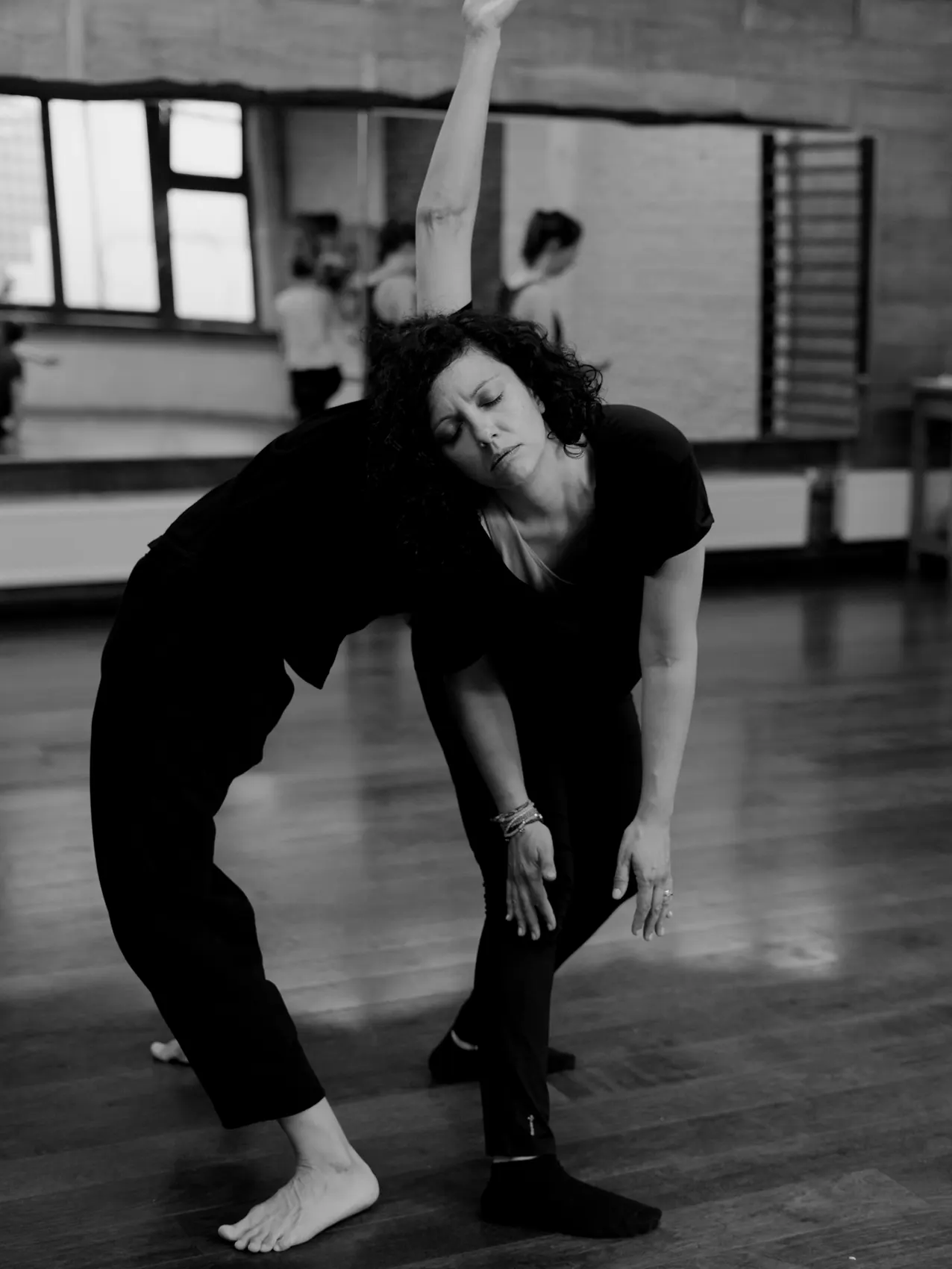 Een danseres buigt voorover met gesloten ogen tijdens een les