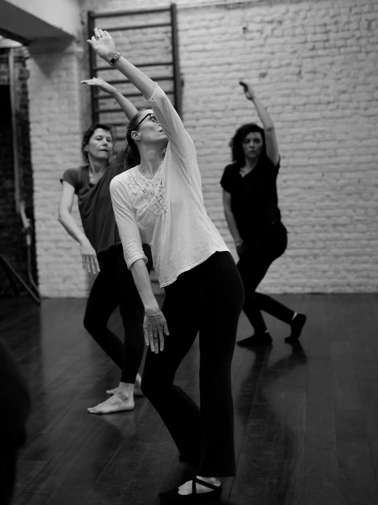 Een groep danseressen met geheven armen tijdens een les